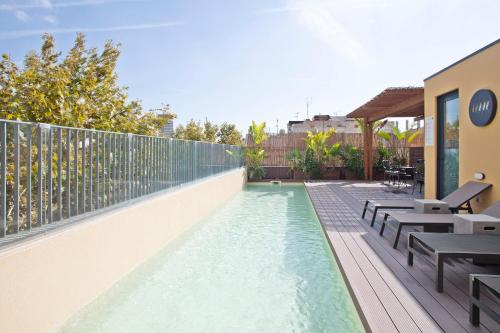 a swimming pool on a balcony with tables and benches at Niu Barcelona Hotel in Barcelona