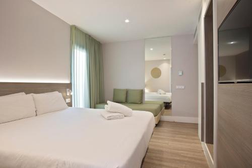 a bedroom with a large white bed and a couch at Niu Barcelona Hotel in Barcelona