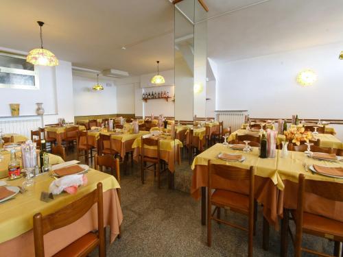 een eetkamer met tafels en stoelen met geel tafelkleed bij Albergo Anita in San Bartolomeo al Mare