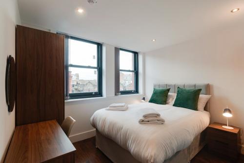 Un dormitorio con una cama con almohadas verdes. en Mathew Street City Centre Apartments by Happy Days, en Liverpool