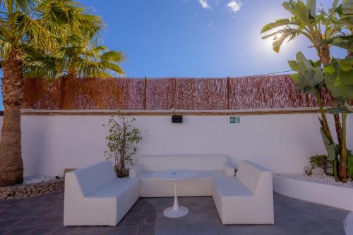a patio with two white chairs and a table and palm trees at Hotel Boutique Sibarys - Adults Recommended in Nerja