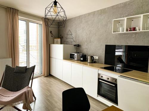cocina con armarios blancos y encimera en Jezerní apartmán s terasou a saunou v Lakepark Residence, en Doksy