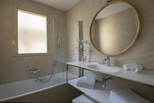 a bathroom with a sink and a mirror and a tub at Hotel Chambord in Menton