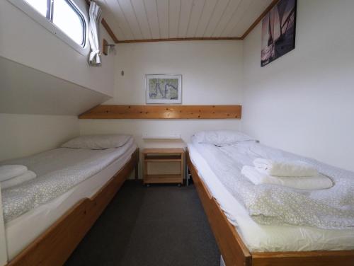 two twin beds in a small room with a window at Hotelboat Allure in Amsterdam