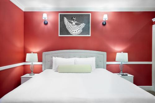 a red bedroom with a white bed and two lamps at Hotel la Perla Leon in León