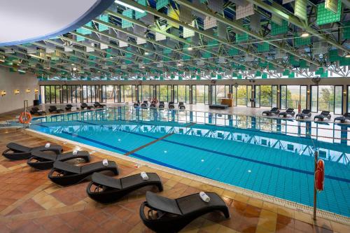 a large swimming pool with black chairs in a building at Kfar Giladi Hotel in Kefar Gil‘adi