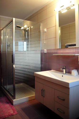 a bathroom with a sink and a shower with a mirror at Haven Beach in Faliraki