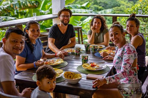 un grupo de personas sentadas alrededor de una mesa comiendo comida en Casa AliBri en Santa Marta