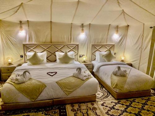 a bedroom with two beds in a tent at Palmyra Luxury Camp in Merzouga