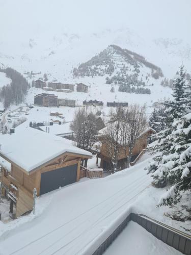 a snow covered building with a mountain in the background at Appartement 8 couchages 45 m2 tout confort à la foux d'allos in La Foux
