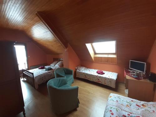 a attic room with two beds and a television at L'éloge de la Nature in Corps
