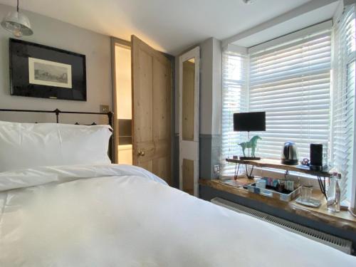 - une chambre avec un grand lit blanc et une fenêtre dans l'établissement 27 Brighton Guesthouse, à Brighton et Hove