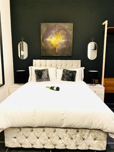 a bedroom with a large white bed with black walls at Duke and Duchess Apartments and Rooms - Private in Room Hot Tub Suites in London