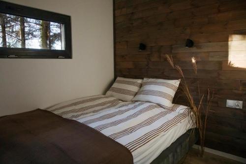 a bed in a room with a wooden wall at Odpoczynek Domki Pod Dębem z Opcją Jacuzzi in Ćmińsk