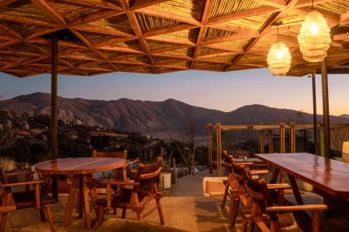 a patio with tables and chairs with mountains in the background at Encuentro Guadalupe in Valle de Guadalupe