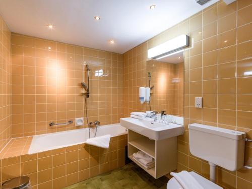 Un baño con lavabo, bañera e inodoro. en Hotel Hubertus, en Fügenberg