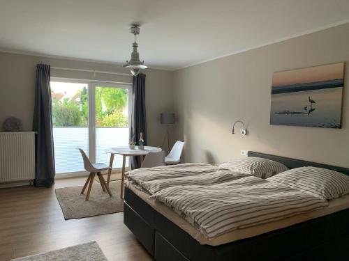 Schlafzimmer mit einem Bett, einem Tisch und einem Fenster in der Unterkunft Appartement Meerzeit - a62529 in Laboe