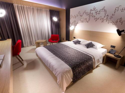 a bedroom with a large bed and two red chairs at Park Boutique Hotel in Varaždin