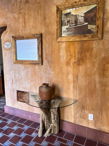 a table with a pot on a tree stump against a wall at Mesón de las Delicias in Cuernavaca
