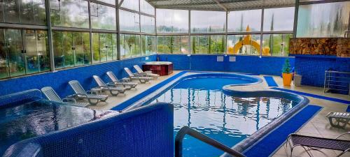 a large swimming pool in a building with chairs around it at Hotel Nacional Inn Campos do Jordão in Campos do Jordão