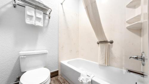 a white bathroom with a toilet and a bath tub at Atria Hotel and RV McGregor in McGregor