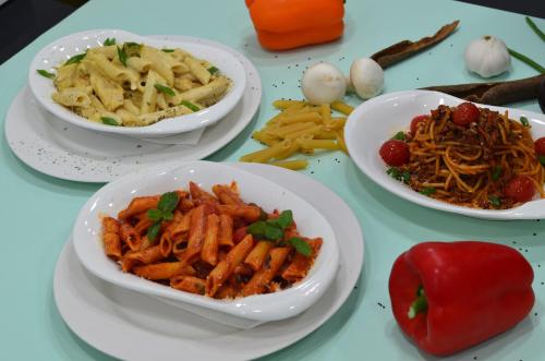 a table topped with plates of food and bowls of pasta at Blaire Executive Suites in Manama