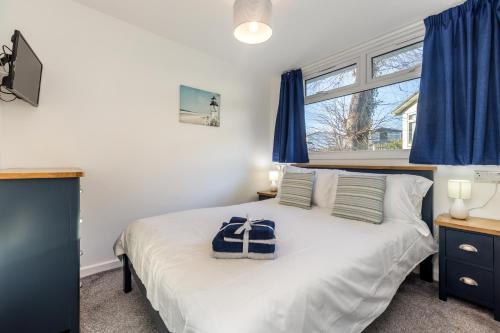 a bedroom with a bed with blue curtains and a window at 429 Norton Park in Dartmouth