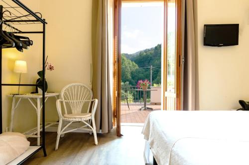 a bedroom with a bed and a chair and a window at Hotel Il Perlo in Bellagio