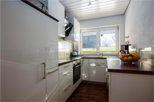 una cocina con armarios blancos y un bol de fruta en la barra en Wohlfühloase, en Eisenbach