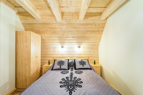 a bedroom with a bed in a wooden room at Komfortowe domki na wynajem - Holiday Tatry in Poronin