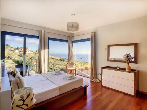 a bedroom with a bed and a view of the ocean at Villa Serramar in Estreito da Calheta