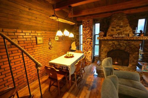 a living room with a table and a stone fireplace at Rustic cottage JARILO, an oasis of peace in nature in Ležimir