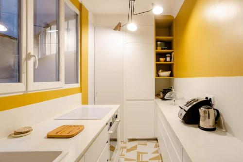 a kitchen with white counters and yellow walls at Bel appartement dans le 9ème in Paris