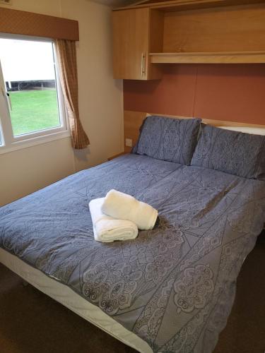 - une chambre avec un lit doté d'une couette bleue et d'une fenêtre dans l'établissement Parkdean Kessingland Beach Holiday Chalet, à Benacre