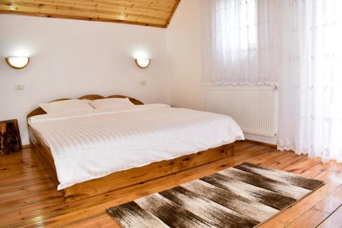 Habitación blanca con cama y alfombra en Casa de sub Horă, en Zărneşti
