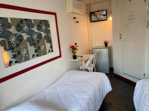 a room with a bed and a table and a desk at Nouvelle Classe Hotel in Châtellerault
