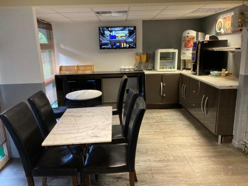 a kitchen with a table and chairs and a tv on the wall at Nouvelle Classe Hotel in Châtellerault