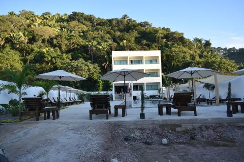 a group of tables and umbrellas in front of a building at MALAKI in Los Ayala