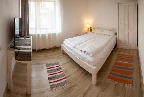 a bedroom with a white bed and a window at Otto's Guesthouse in Prejmer