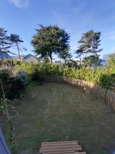 a garden with a wooden fence and trees at Villa Jules Petit Gîte in Agon Coutainville