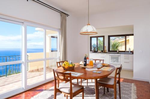 a kitchen and dining room with a table and chairs at Garajau House - Sunrise to Sunset Ocean View Villa in Caniço