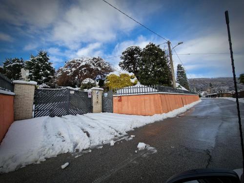 a snow covered street with a fence and a house at B&B Margot in Albavilla