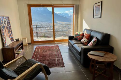 ein Wohnzimmer mit einem Sofa, einem Tisch und einem großen Fenster in der Unterkunft Apt With Panoramic View Near Vauban City in Briançon