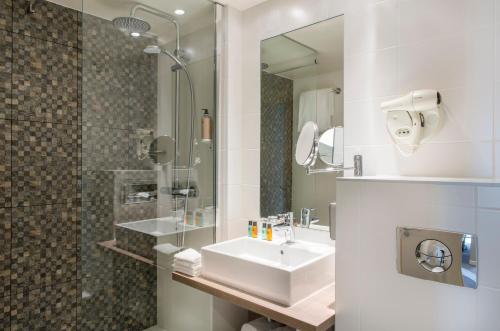 a bathroom with a sink and a shower at Best Western Plus Paris Saclay in Saclay