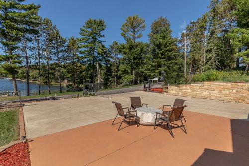 a table and chairs on a patio next to the water at Whitefish Lake Home with Heated Indoor Pool in Manhattan Beach