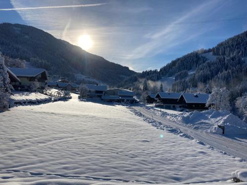 a snow covered village with the sun rising behind a mountain at Landhaus Riepler in Wagrain