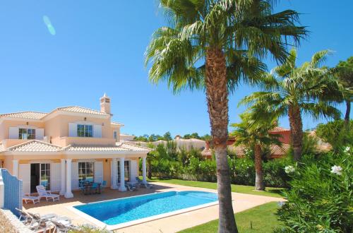 eine Villa mit einem Pool und Palmen in der Unterkunft Villa Dalia by Algarve Vacation in Almancil