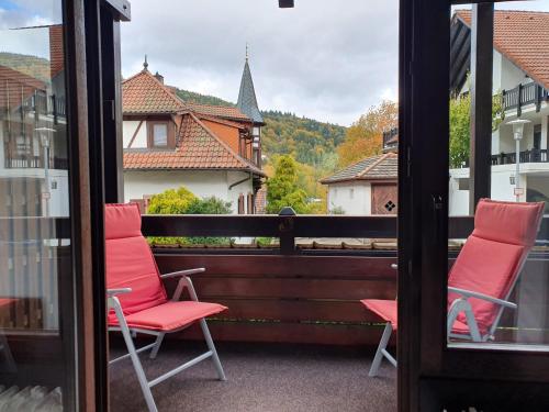 two chairs on a balcony with a view of a house at Gemütliche Ferienwohnung am Kurpark in Bad Herrenalb in Bad Herrenalb