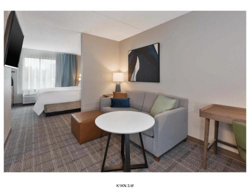 a hotel room with a couch and a table and a bed at Staybridge Suites Pittsburgh Airport by IHG in Pittsburgh