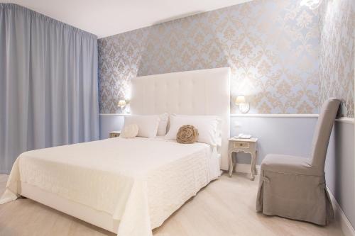 a bedroom with a white bed and a chair at Marina Holiday & Spa in Balestrate